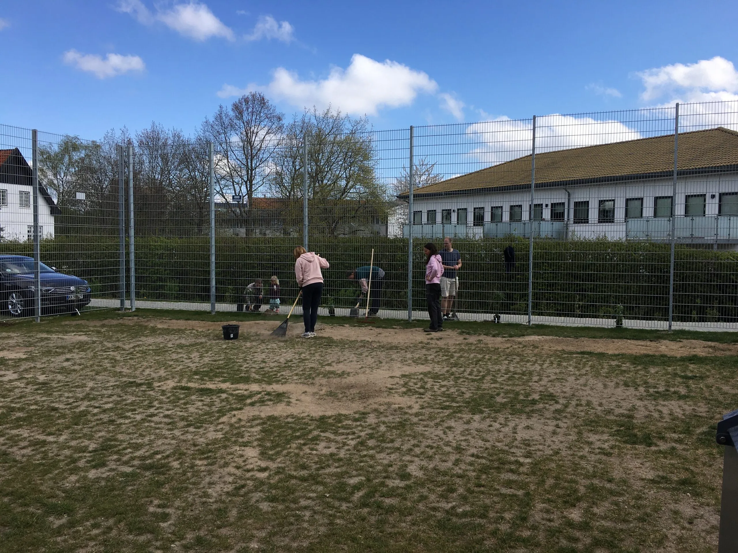 Beboere arbejder på fællesareal med boldbane om foråret