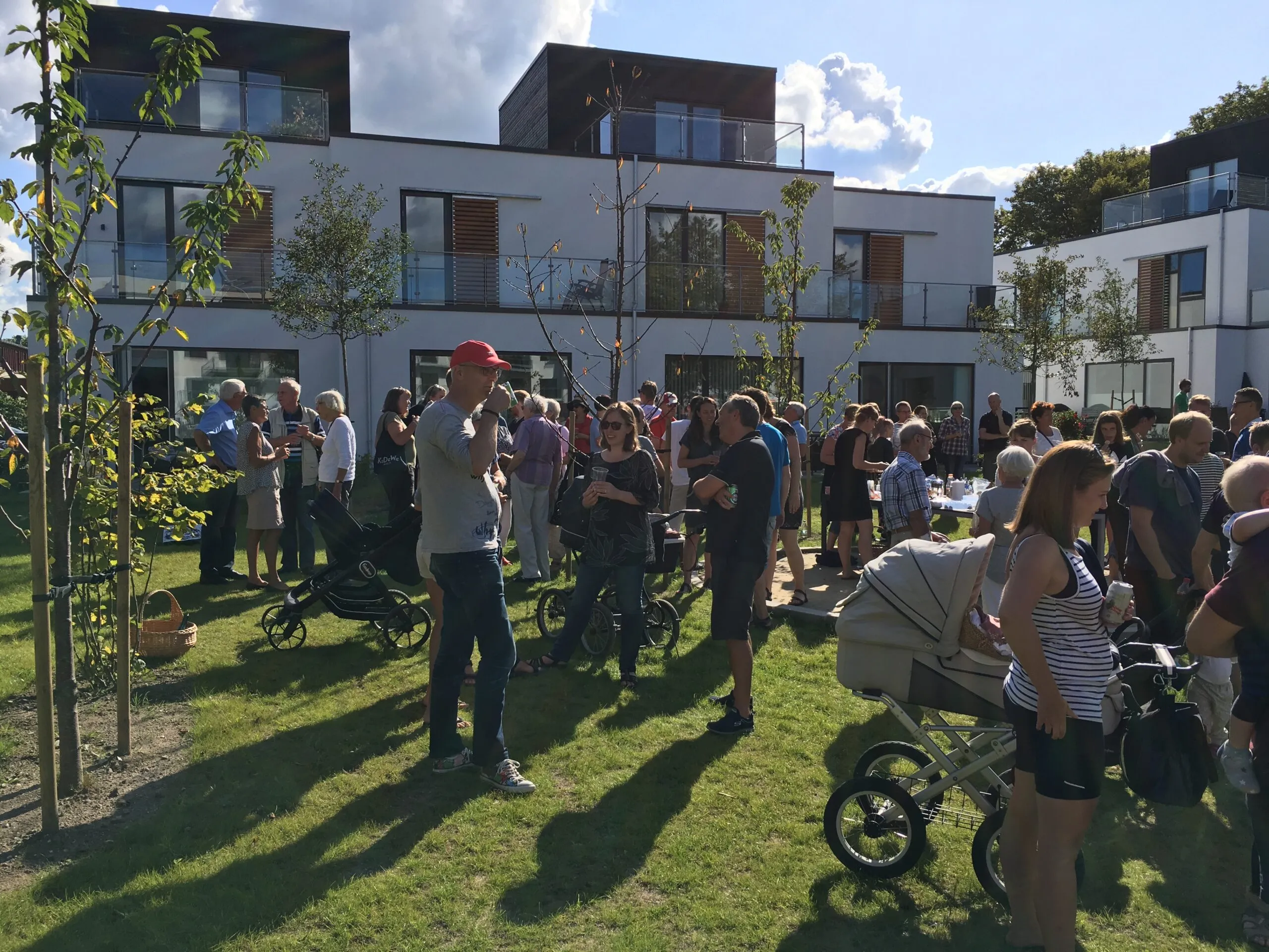 Beboere samlet til sommerfest på grønt fællesareal foran lejlighedsbygninger i Bagsværdlund